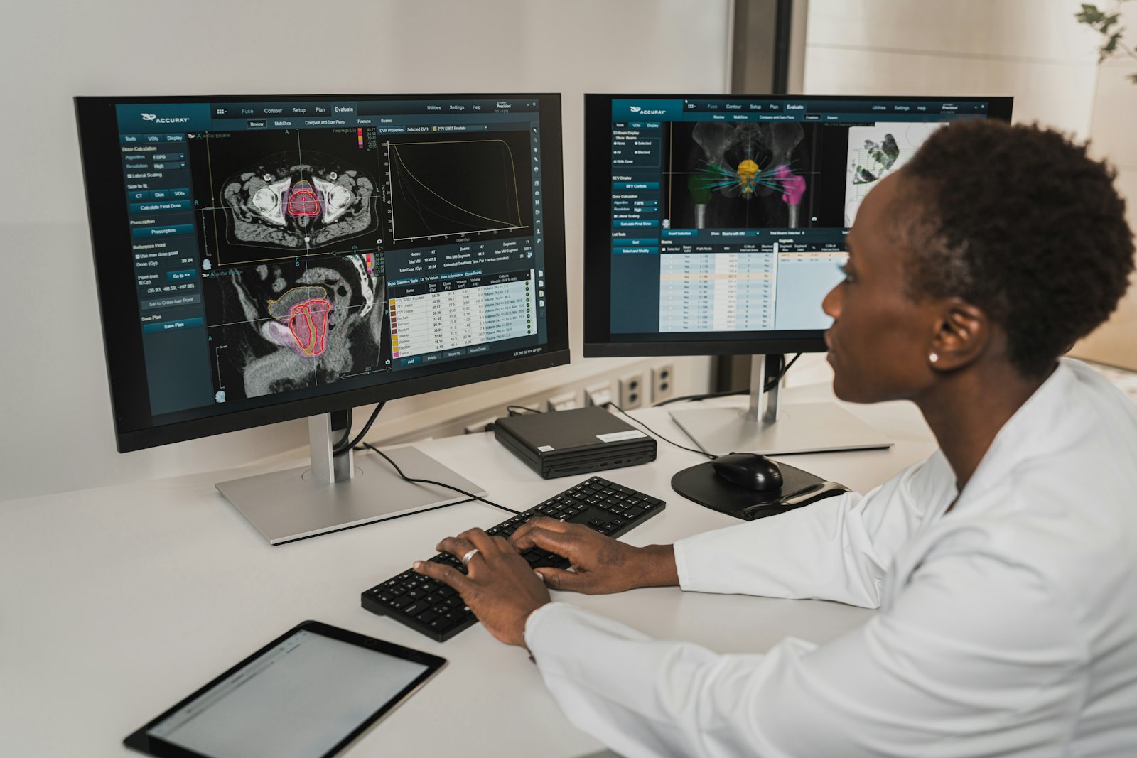 A clinician working at two monitors in a hospital office.